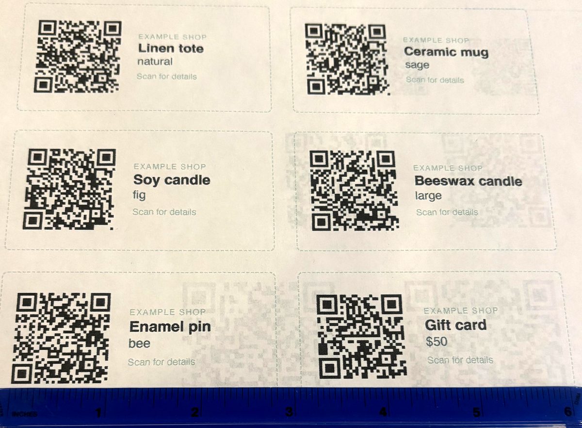 Six QR code product labels printed on plain paper, 3 by 1.5 inches each, with a ruler showing each code is about 1 inch wide
